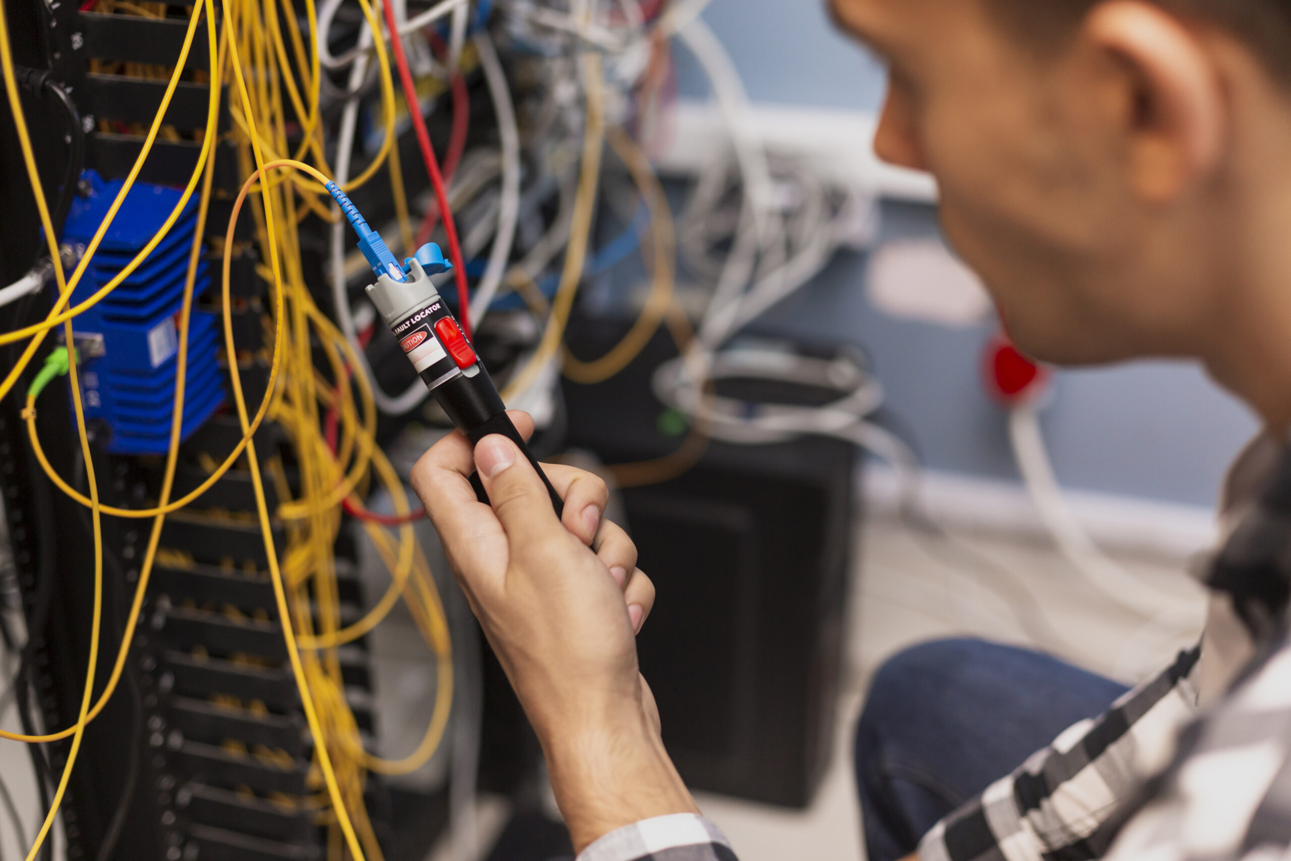 Engineer using a Visual Fault Locator to troubleshoot fiber optic cabling.