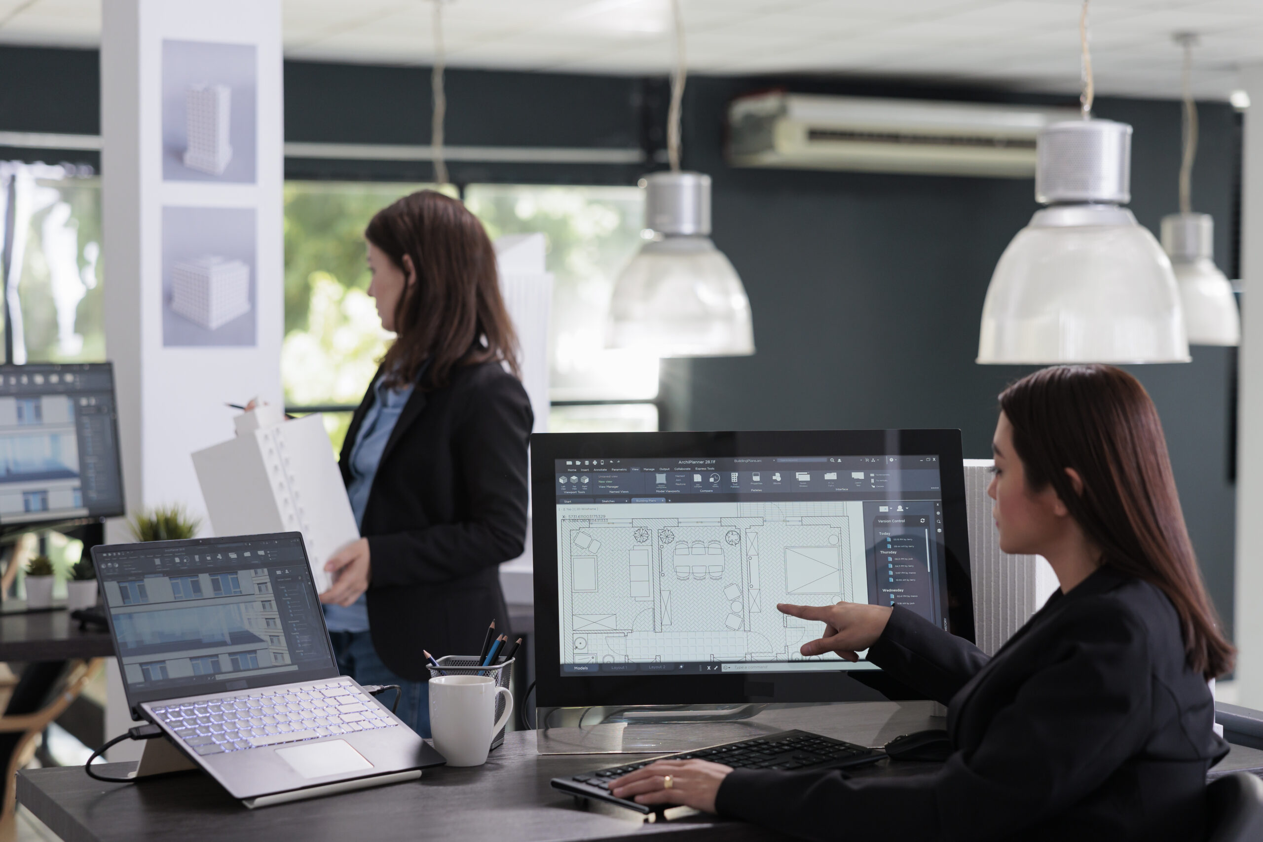Architects reviewing floor plan blueprints on CAD software screens