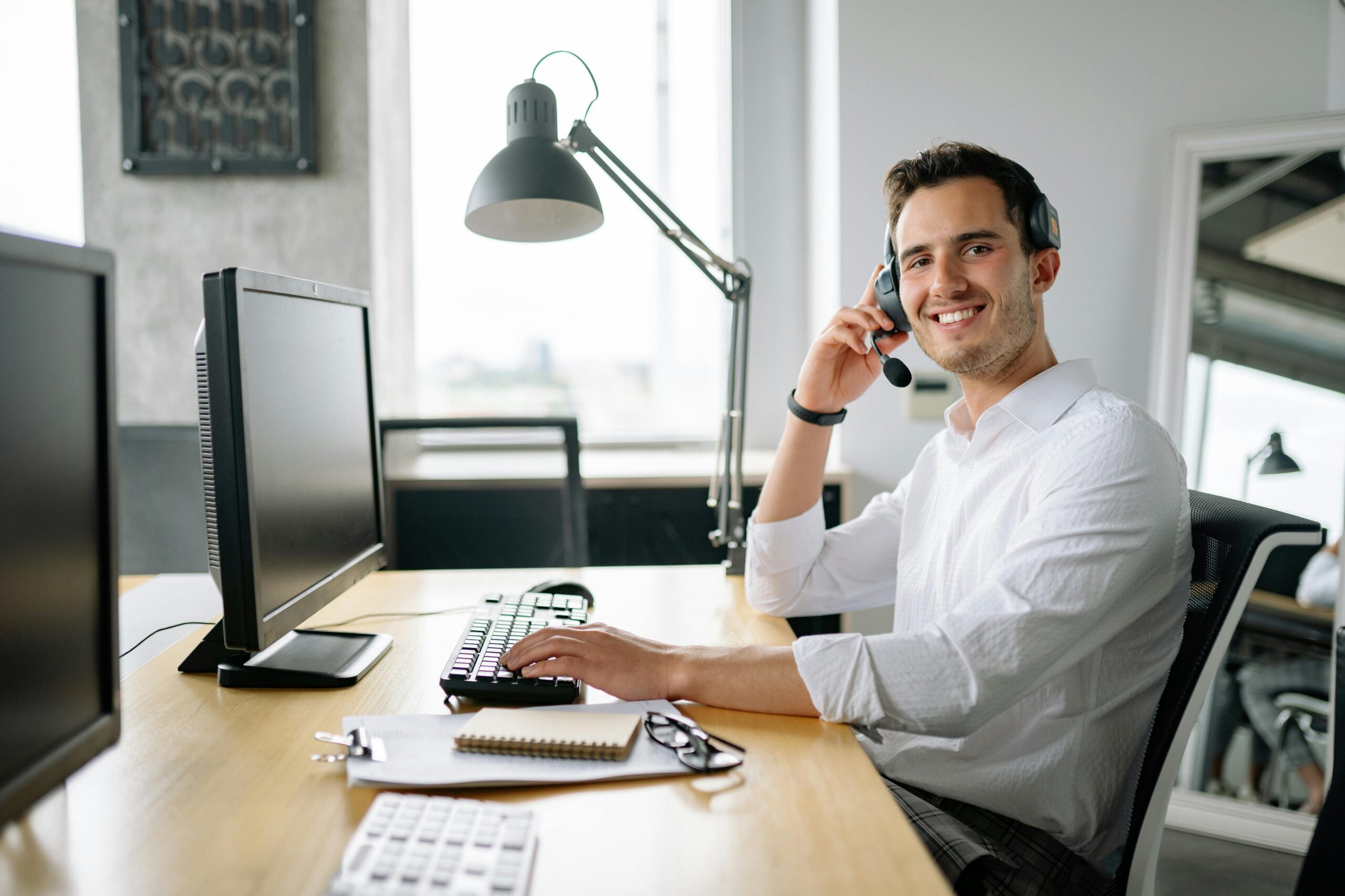 IT support specialist smiling at camera in front of work desk