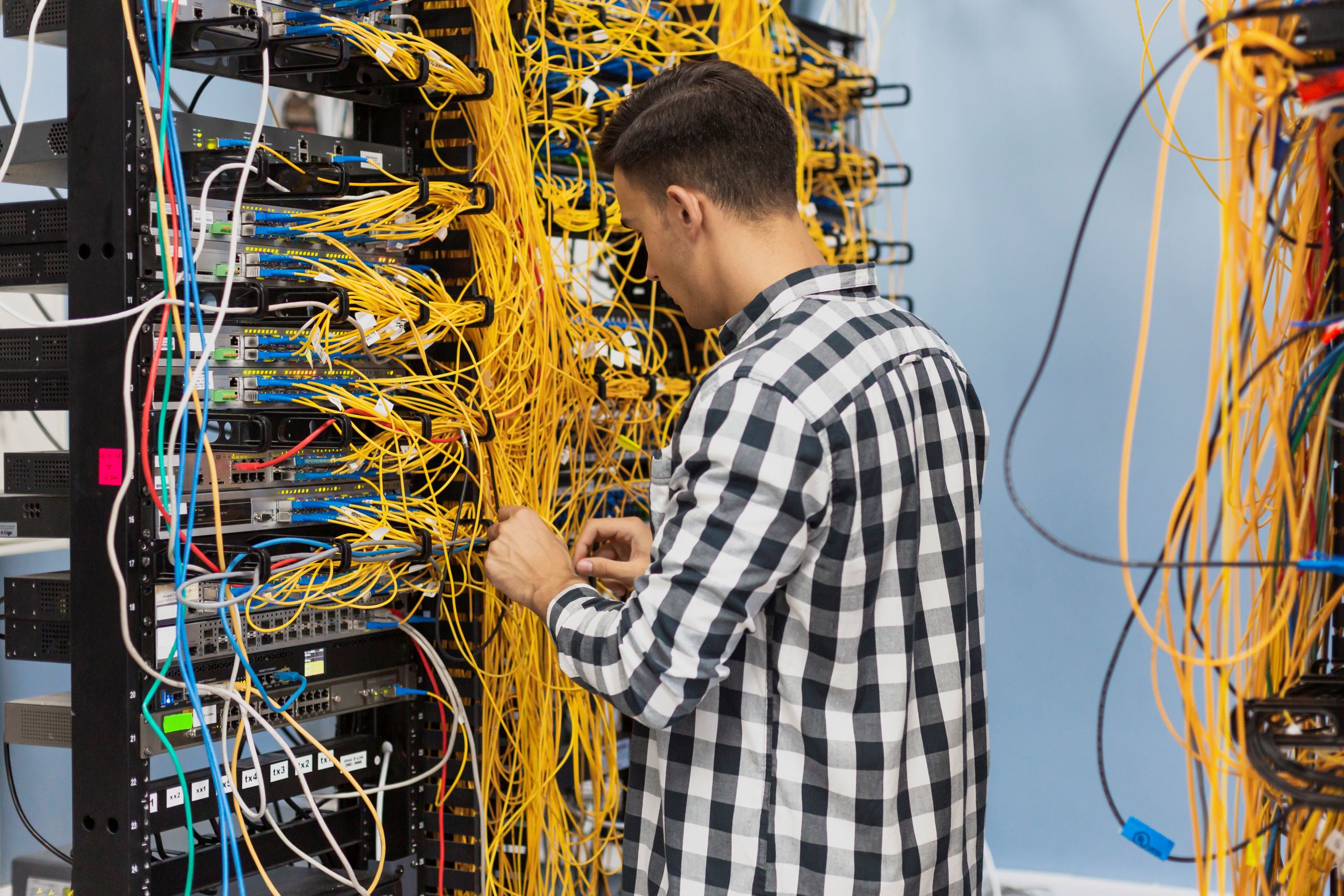 Technician organizing yellow network cables in server rack
