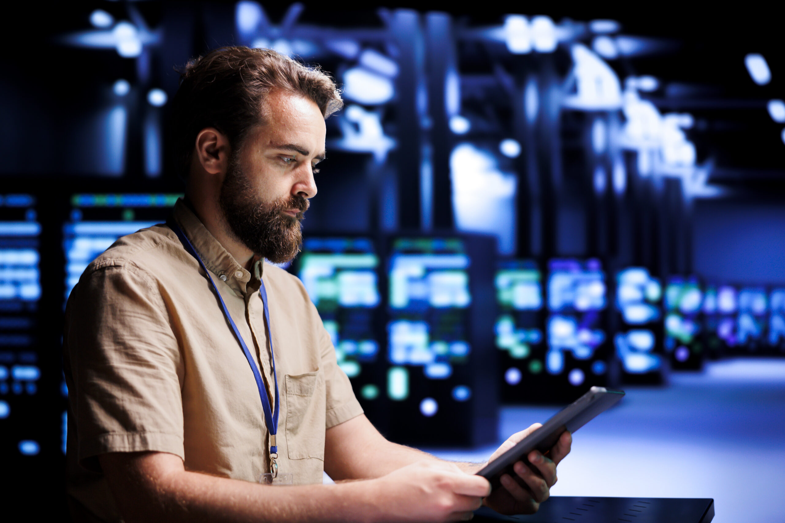 IT technician reviewing tablet in a dark server room.